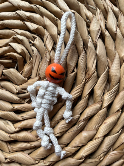 Macrame skeleton decoration made with natural yarn and an orange bead 