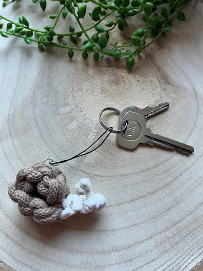 Keychain in the shape of a snail, with a small set of keys on a wooden surface. 
