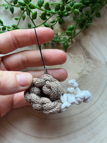 Hand holding a small macrame snail on a wooden surface