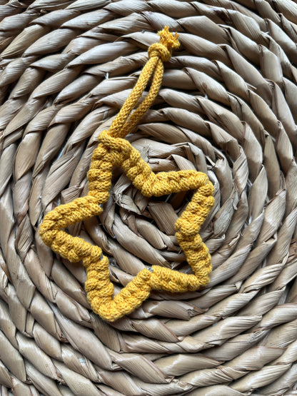 Yellow macrame heart decoration on a woven mat