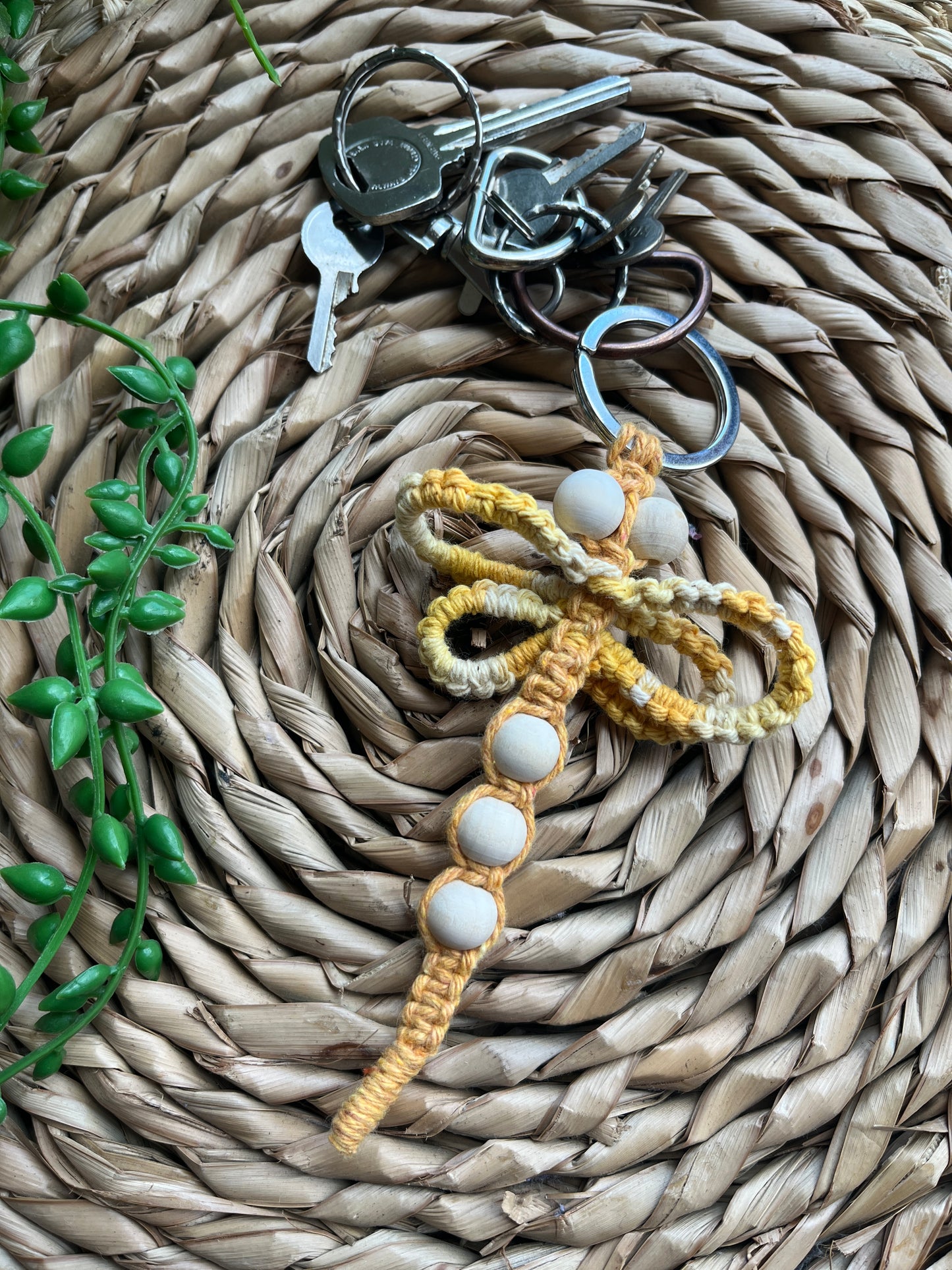Handmade macrame dragonfly keyring or bag charm, made using shades of yellow recycled cotton, on a metal split ring, with small wooden beads. 