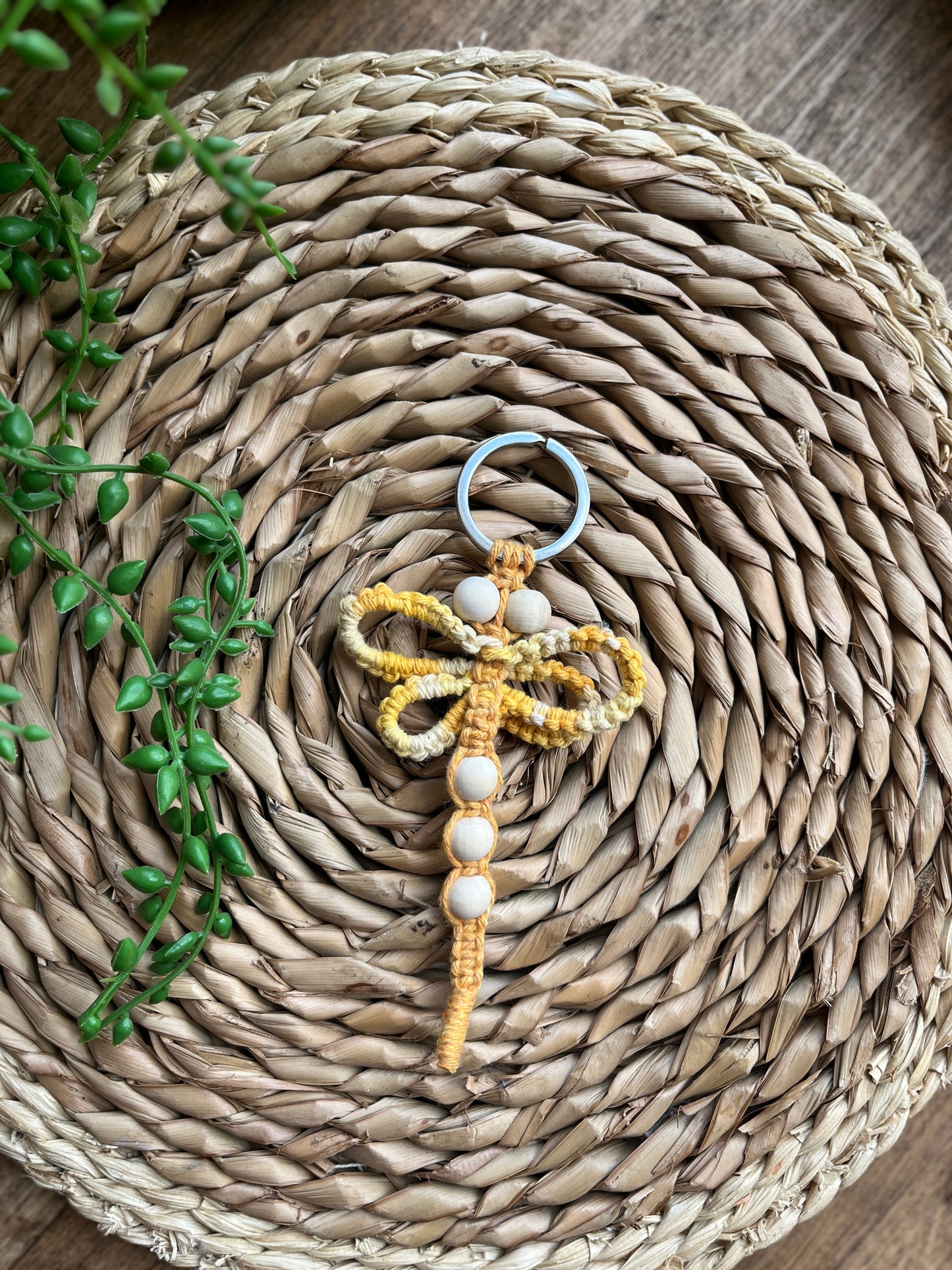 Handmade macrame dragonfly keyring or bag charm, made using shades of yellow recycled cotton, on a metal split ring, with small wooden beads. 