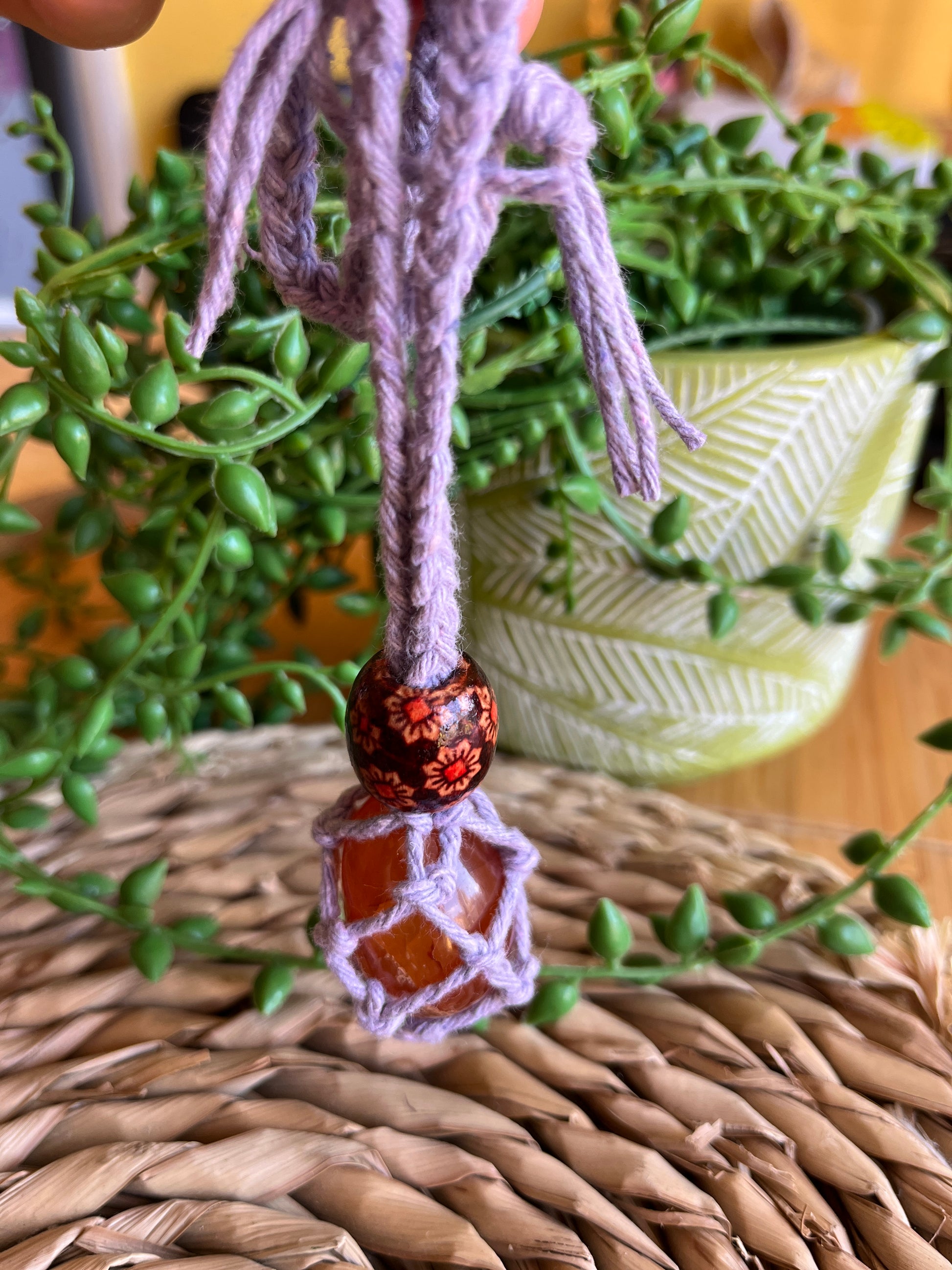 Macrame Gemstone Holder net pouch with blue gemstone inside, made with purple eco friendly recycled cotton and a Wooden bead. 