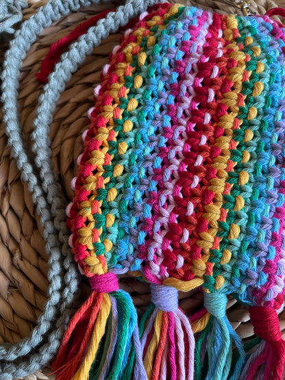 Close up of the intricate knots on a macrame crossbody bag, made with rainbow yarn, with tassels at the bottom. 