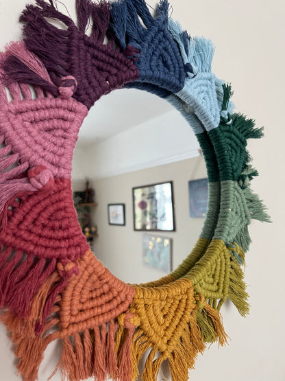 Close up of a round wall hanging mirror with rainbow mandala frame.