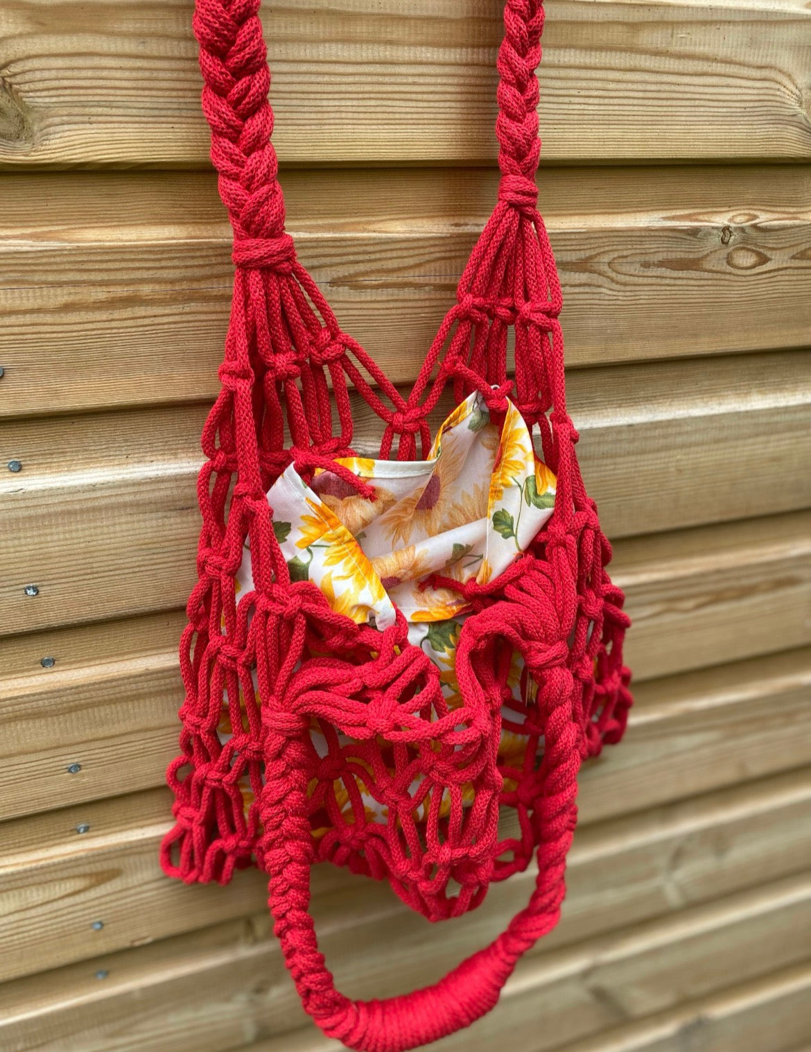Red macrame bag with a sunflower patterned lining against a wooden background