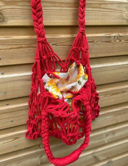 Red macrame bag with a sunflower patterned lining against a wooden background