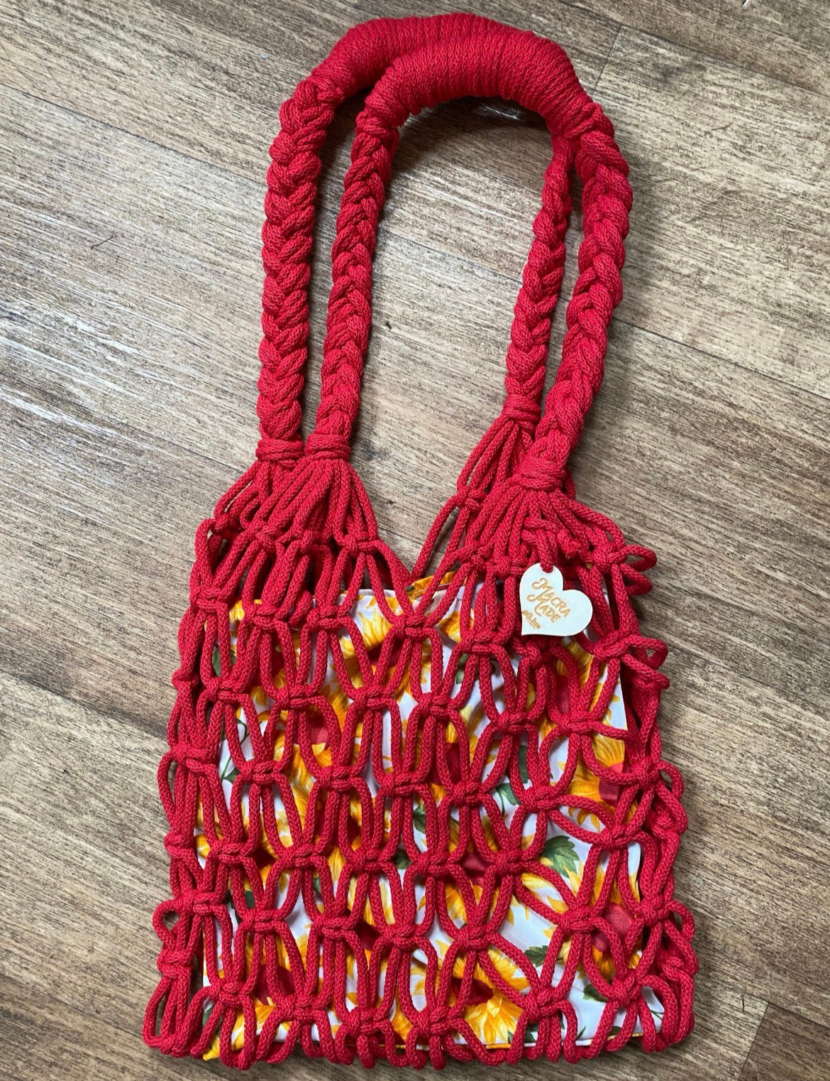 Red macrame bag with a floral patterned lining on a wooden surface
