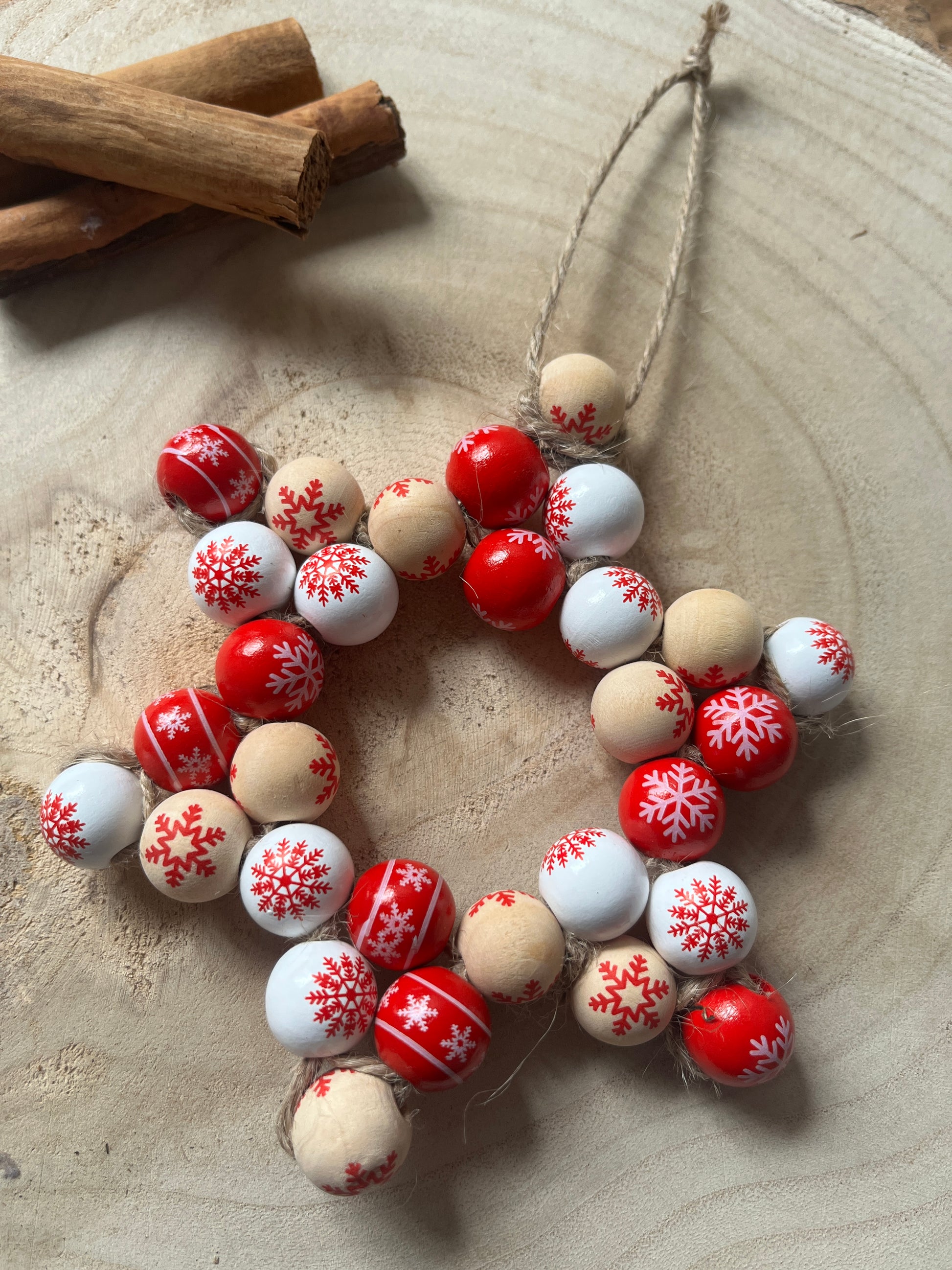 Decorative string of red, white, and beige beads with snowflake patterns on a textured surface.