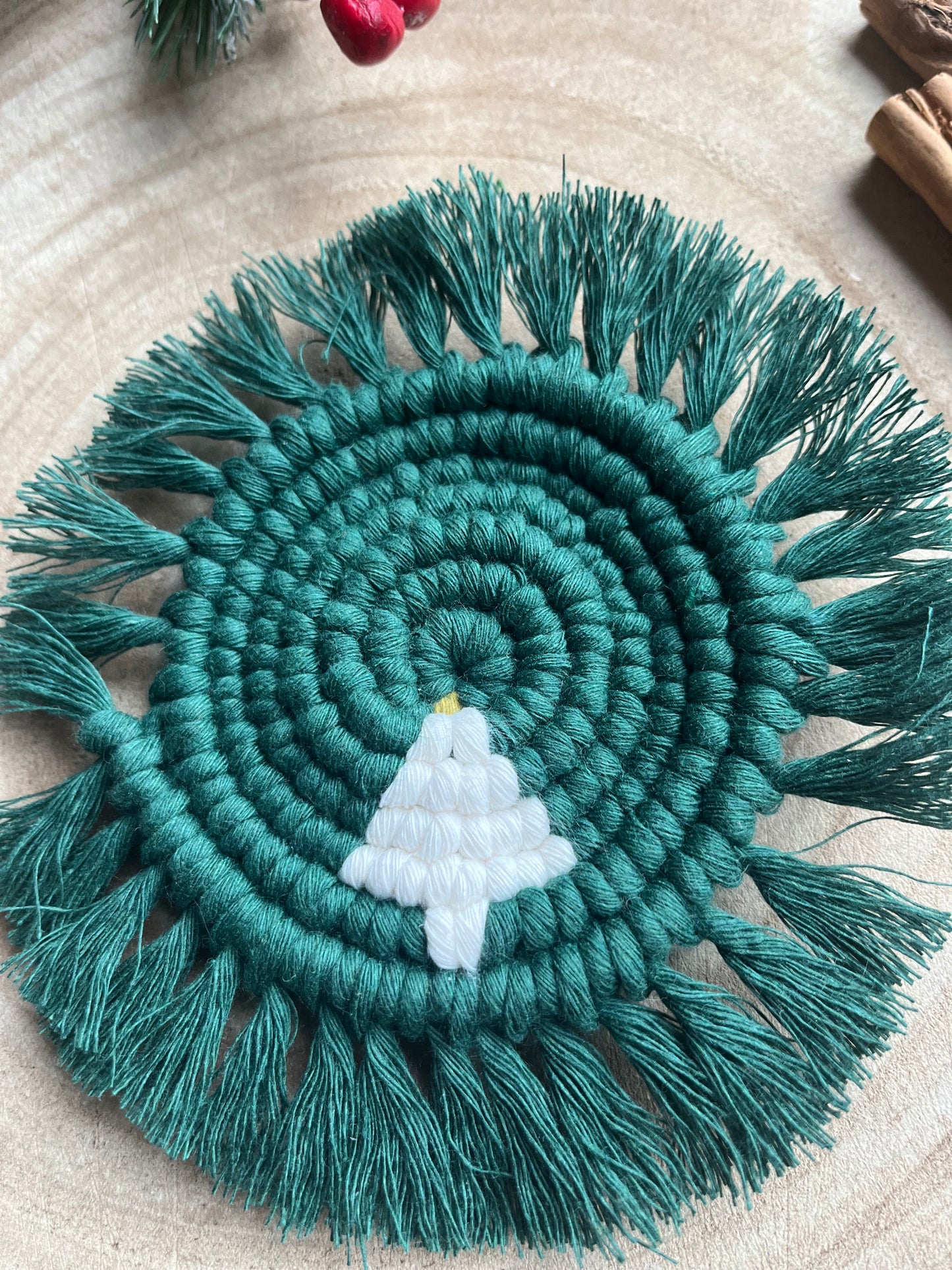 Round macrame coaster with a small christmas tree accent and fringed edge. Handmade with recycled cotton yarn in a pine green colour. 