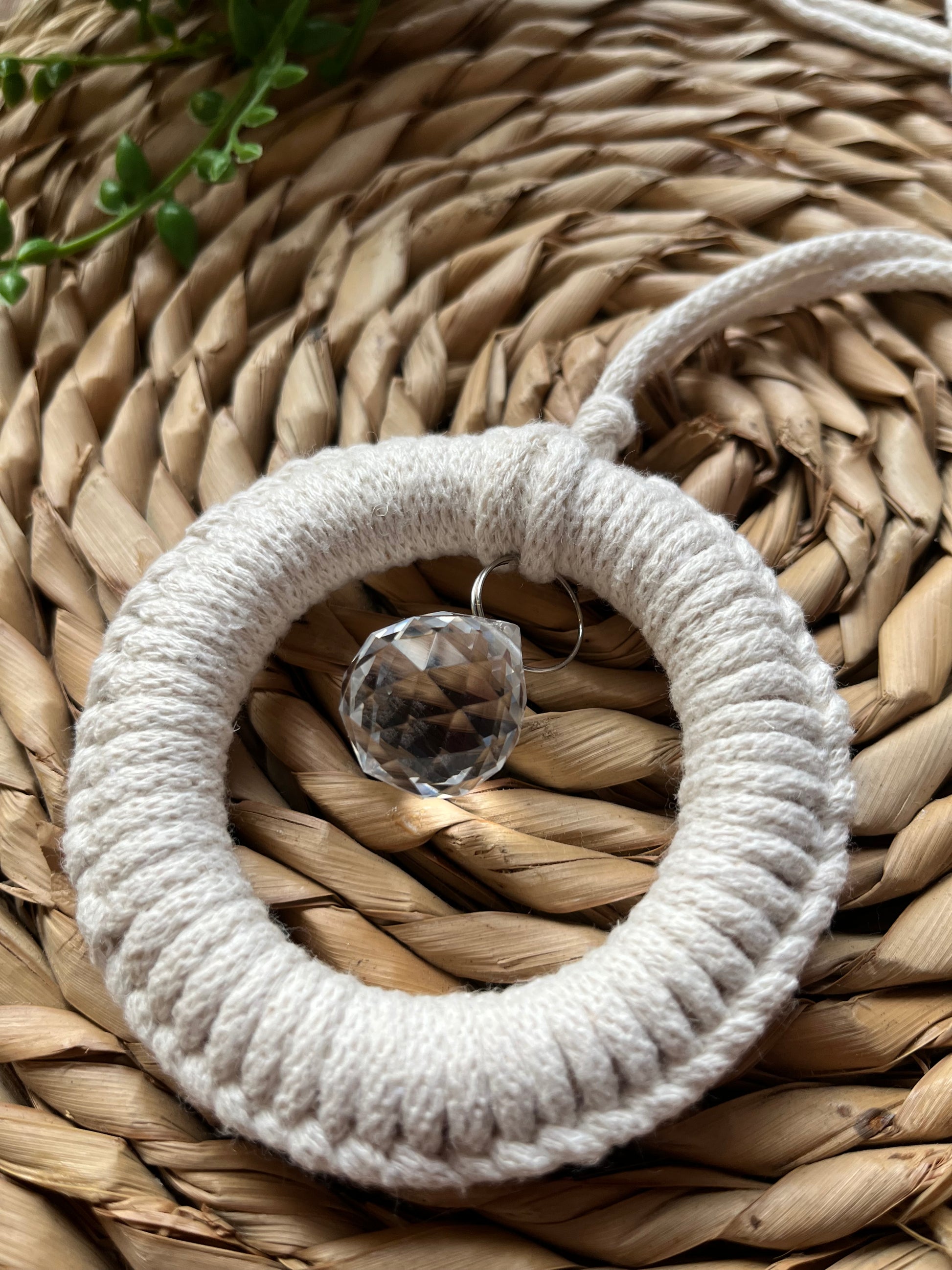 Handmade macrame circular suncatcher, made using recycled cotton in a natural colour, with a small crystal prism. 
