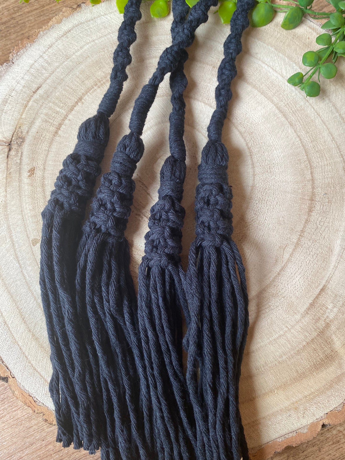 A pair of knotted macrame tassel tiebacks, made with black cotton yarn. 