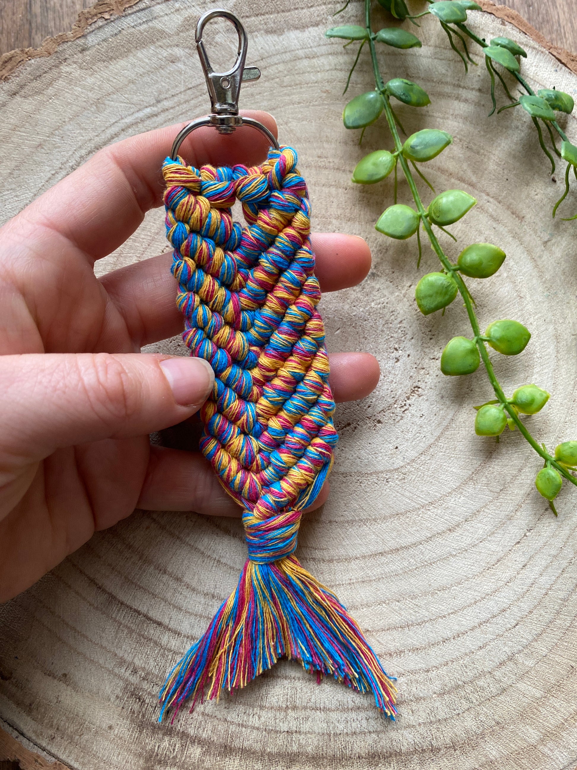 A handmade macrame keyring, knotted using brightly coloured recycled cotton in the shape of a mermaids tail, and finished with a metal lobster clasp. 