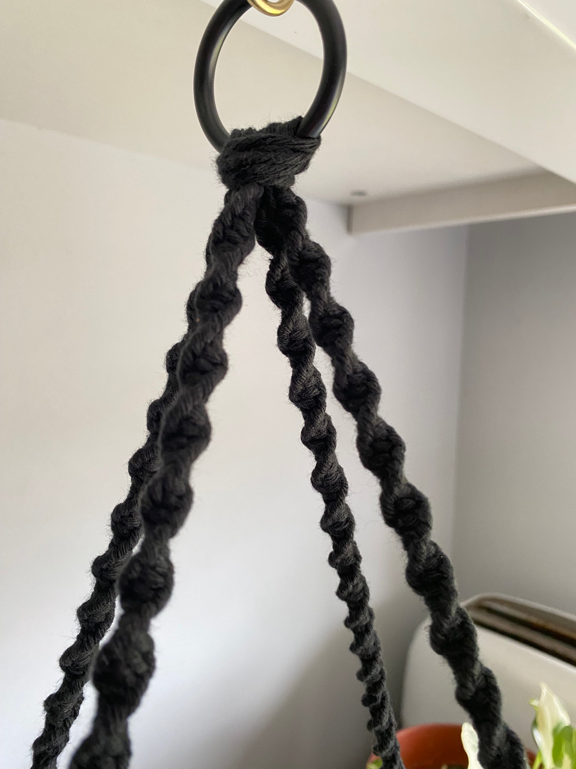 Close up image of black macrame ropes on a metal hoop.