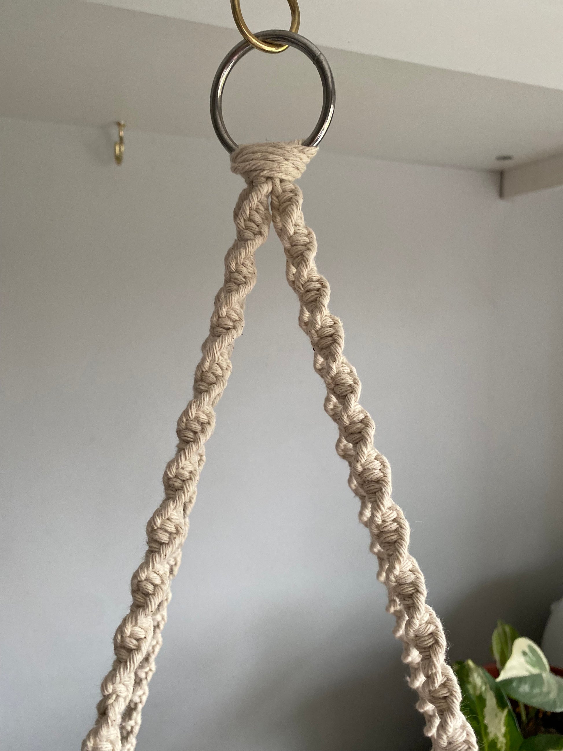 A close up image of natural macrame ropes on a metal hoop.