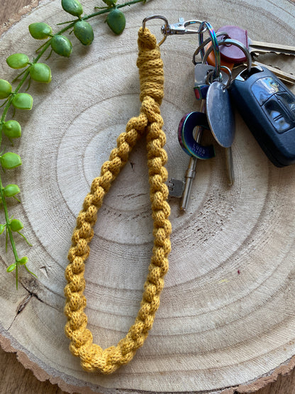 Handmade macrame wristlet keychain with metal clasp, made with mustard yellow recycled cotton. Shown attached to a small set of car keys. 