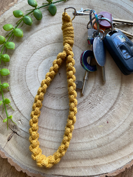 Handmade macrame wristlet keychain with metal clasp, made with mustard yellow recycled cotton. Shown attached to a small set of car keys. 